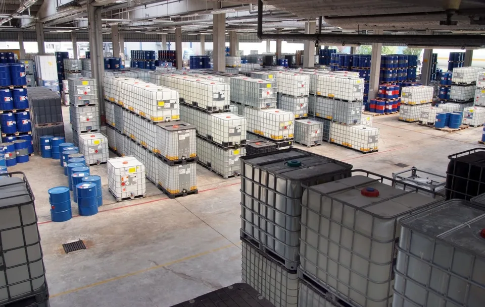Referência visual de recipientes e tambores organizados em um armazém industrial