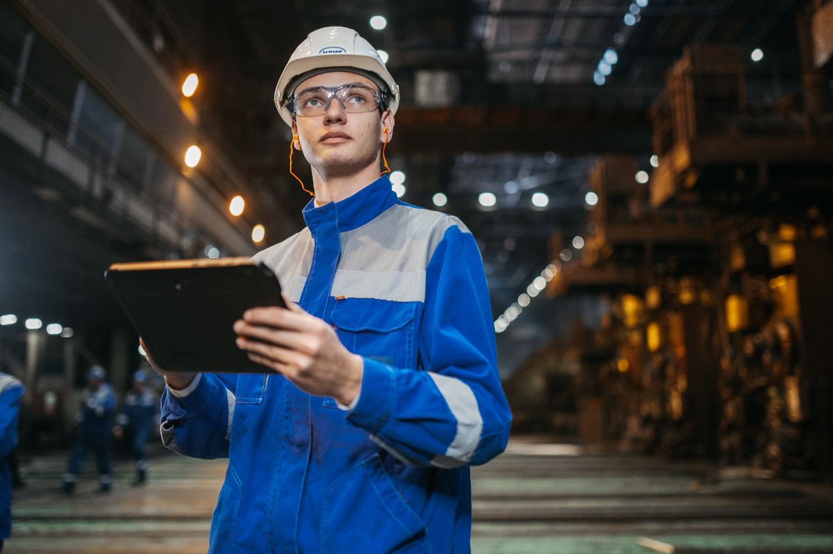 Profesional con casco consultando una tableta en un entorno industrial