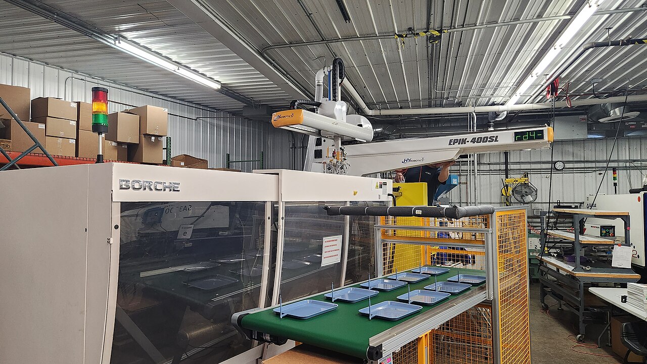 Injetora de plástico com equipamento de manipulação automatizada em ambiente industrial